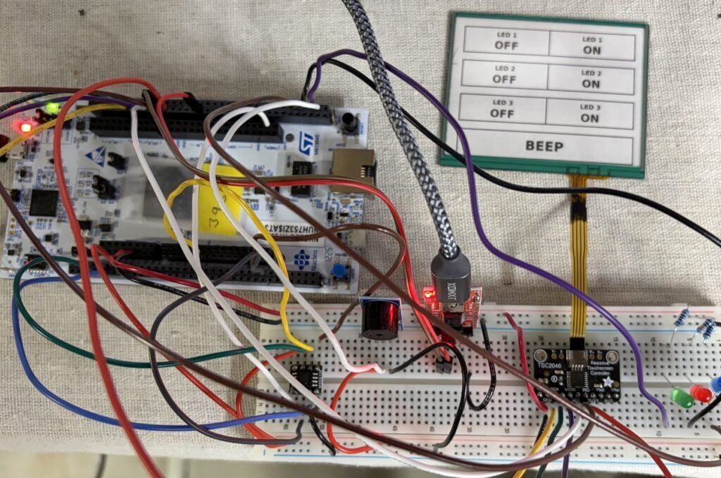 Assembled STM32 resistive touch screen breadboard: Nucleo-H753ZI, TSC2046 controller, buzzer and LEDs, and the touch panel with its printed layout, plus a W25Q128 flash breakout left over from an earlier tutorial
